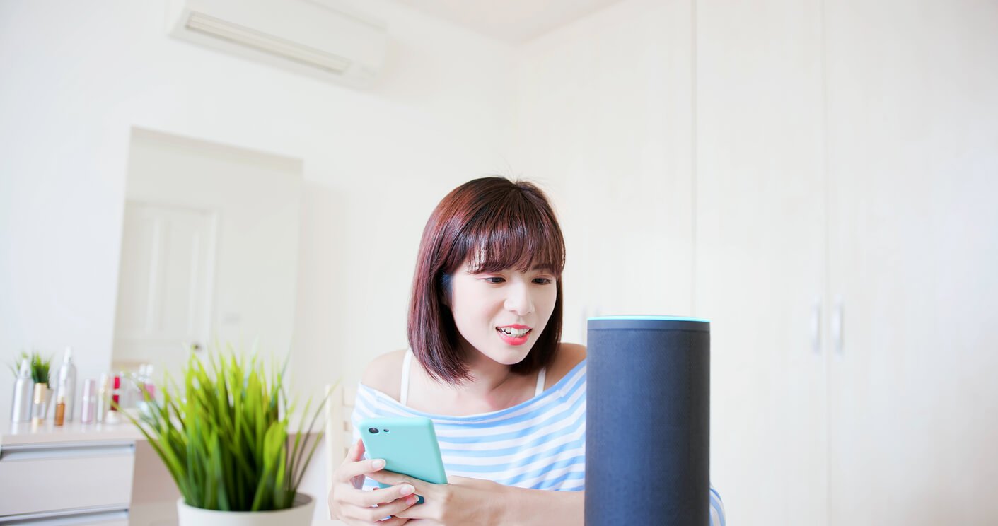 Woman giving voice commands to alexa echo or google assistant smart device