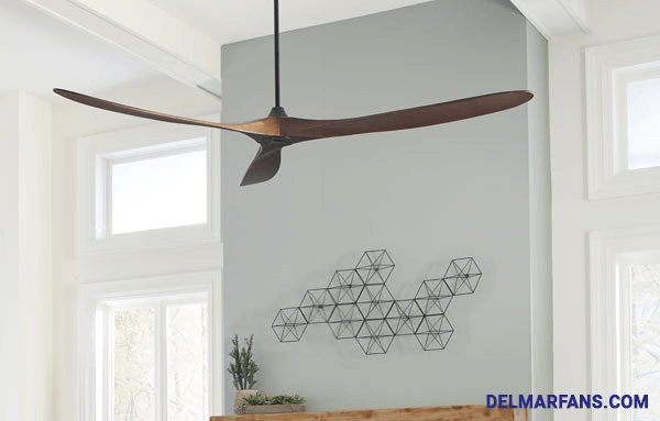 A large, sleek ceiling fan with three blades in a contemporary living room scene.