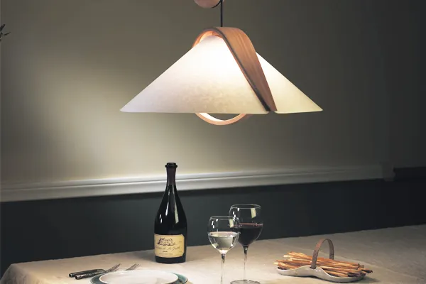 Pictured is white-shaded light over a dining table with plates and wine.